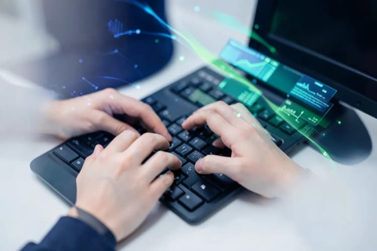 Mãos digitando em um teclado de computador com gráficos de dados flutuando ao redor.