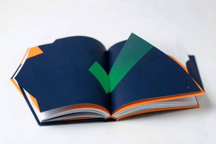 Livro aberto com um símbolo de 'check' sobreposto, indicando conformidade e boas práticas.